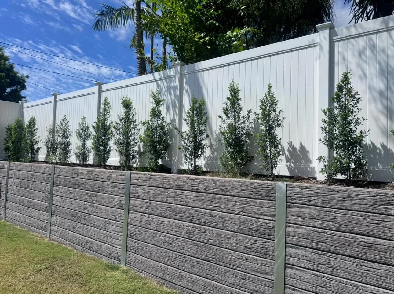Privacy PVC fence on retaining wall with landscaping