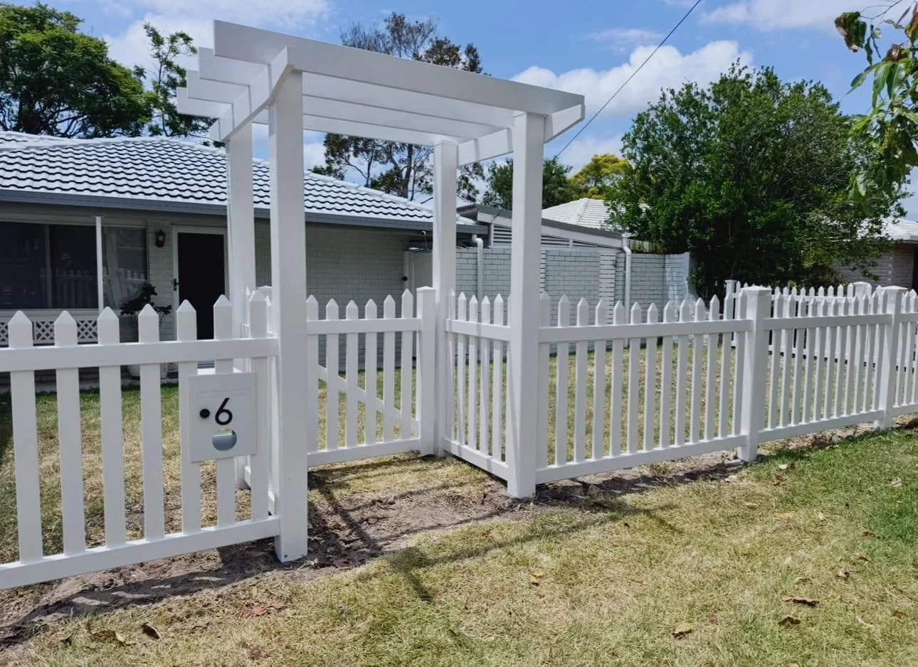 Installed white PVC picket fence with an arbour gate and integrated letterbox