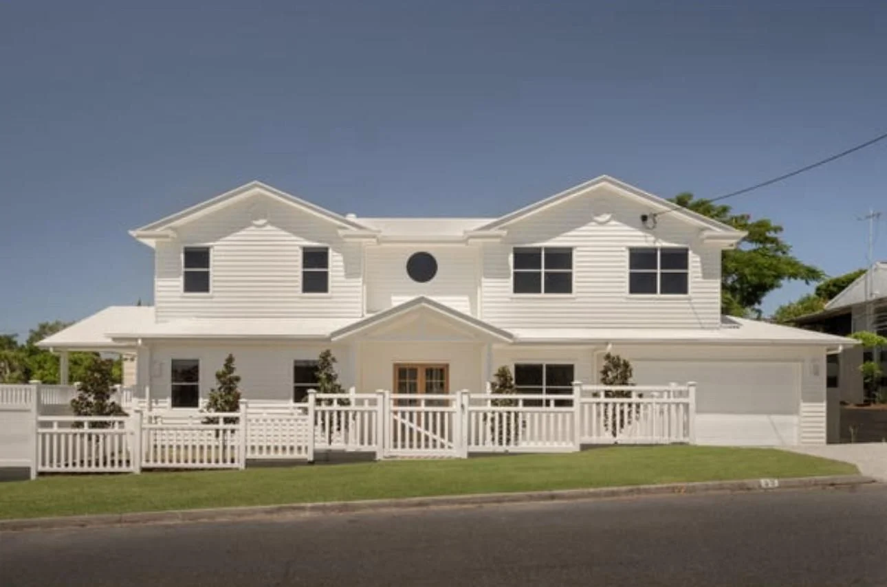 White PVC fence with a flat top line running across a large Hamptons-style Gold Coast home frontage, shown for contrast with a pointed picket profile